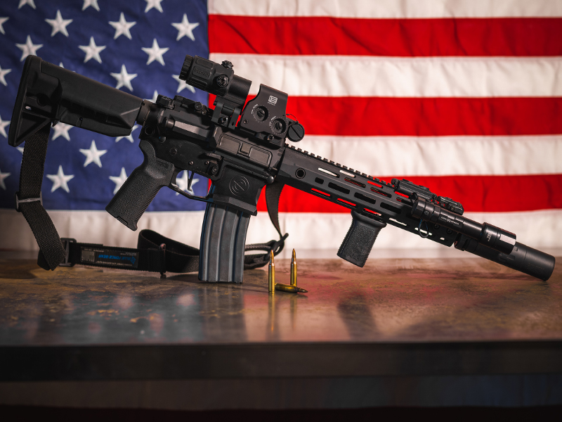 suppressed AR-15 in front of American flag