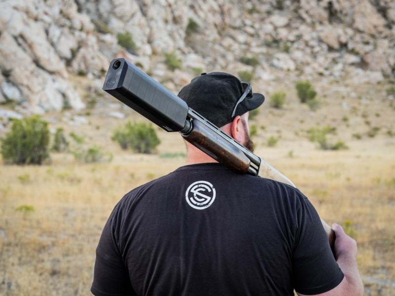 Man wearing a SilencerCo T-shirt shoulders a shotgun with Salvo 12 suppressor attached.