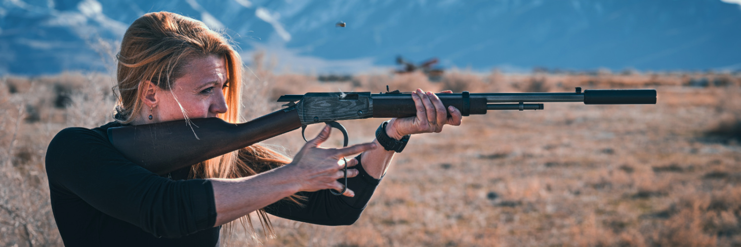 Woman shooting lever action rifle with silencer