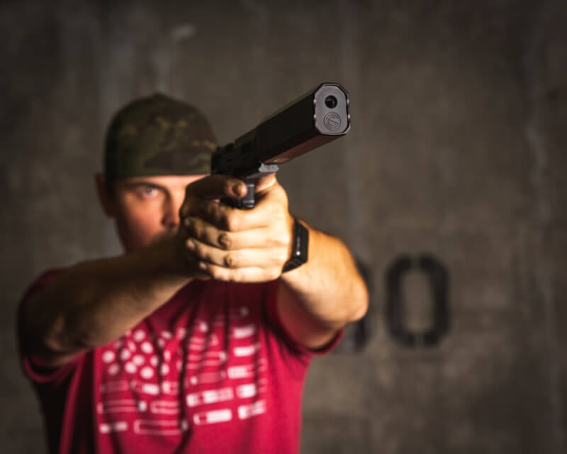 man aiming a pistol with a SilencerCo Osprey 9 dedicated 9mm suppressor