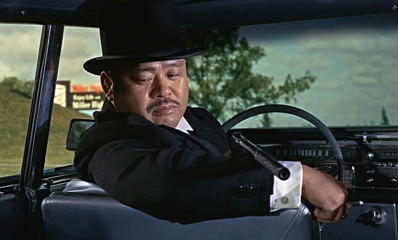 Goldfinger's henchman, Oddjob, with a suppressed pistol. Silencers in cinema