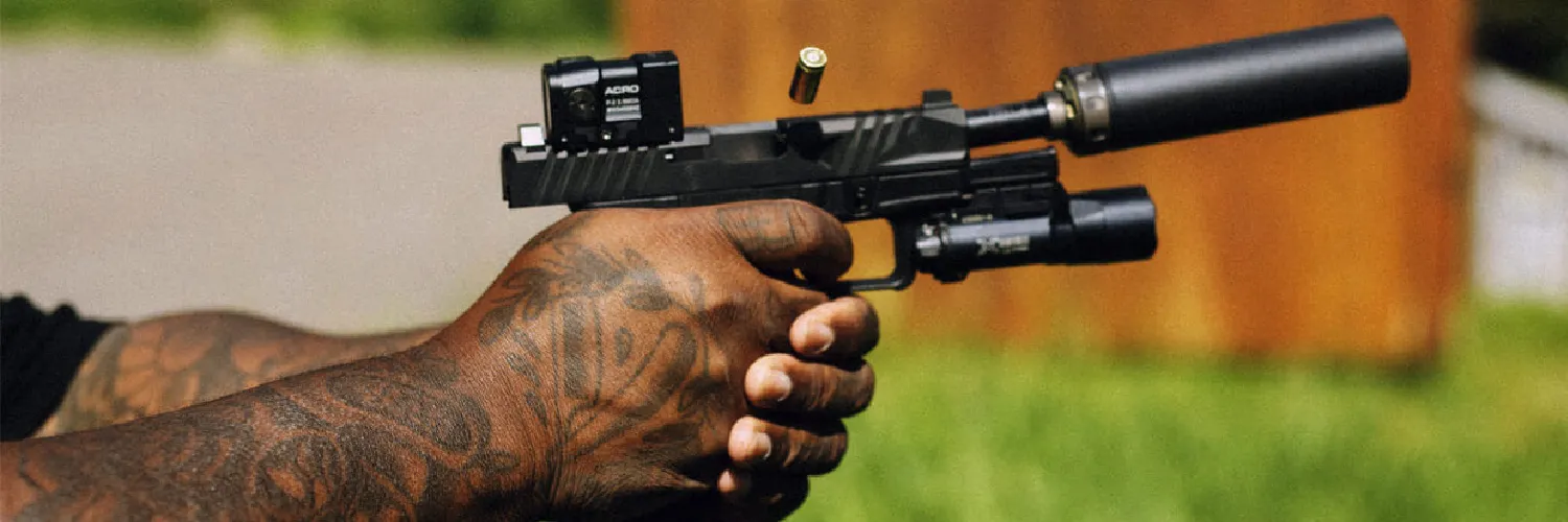 Spectre 9, Aimpoint Acro and Surefire weaponlight on a cycling handgun with spent cartridge flying from ejection port. best handgun suppressors for 2025