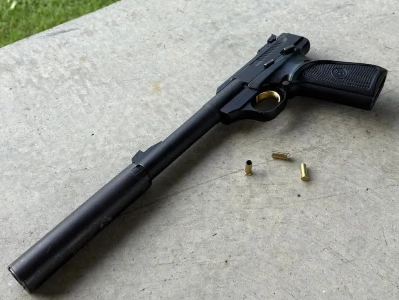 Browning Buckmark rimfire pistol with SilencerCo Sparrow 22 attached, spent casings scattered nearby