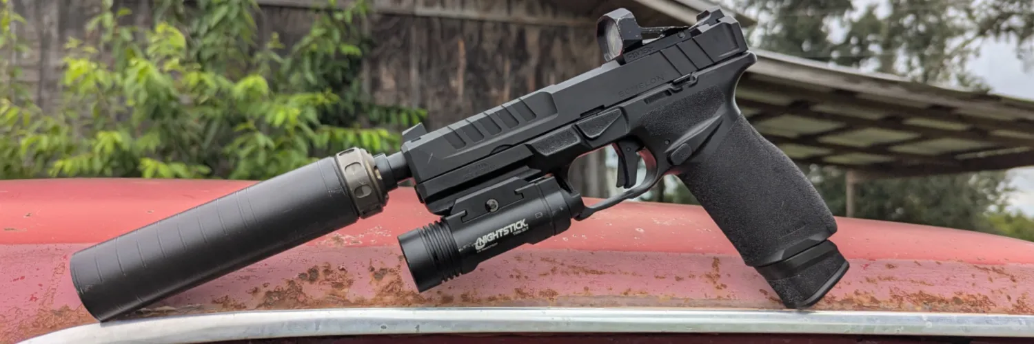 Springfield Echelon with red dot, Nightstick weaponlight, and Silencerco Spectre 9 suppressor on hood of an old rusty red truck, barn in the background.