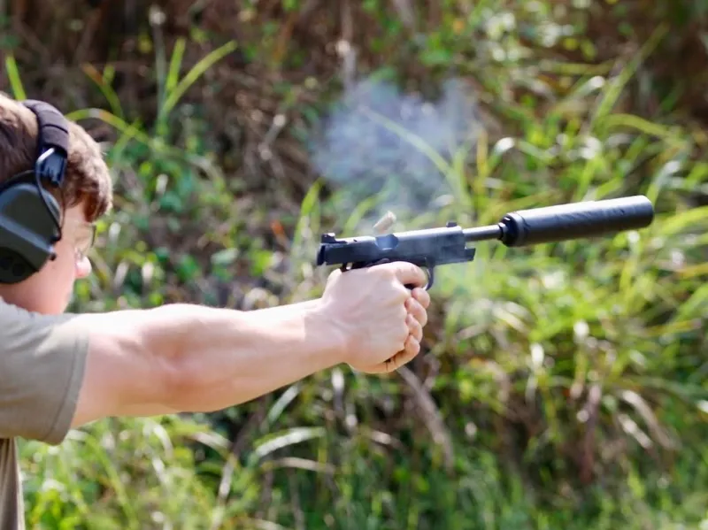 man shooting a suppressed .45 ACP pistol - Springfield Operator 1911 with SilencerCo Hybrid 46M