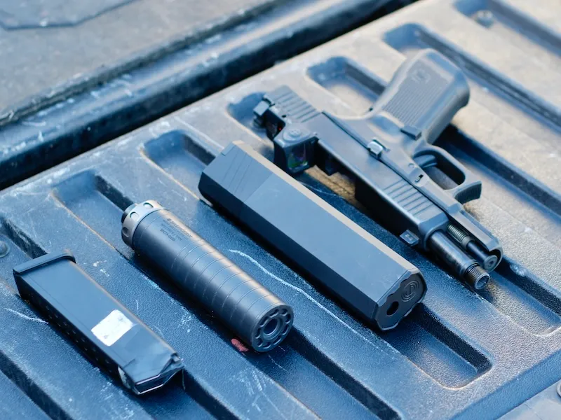 Osprey and Spectre 9 SilencerCo Suppressors on truckbed with field-stripped glock pistol