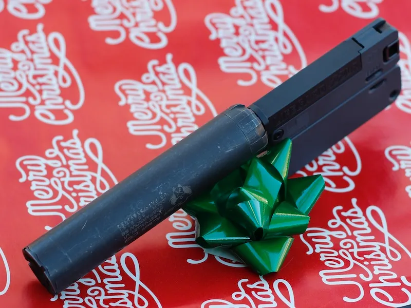 lifecard 22 pocket gun, suppressed, with a SilencerCo Sparrow, on Christmas wrapping paper with green bow