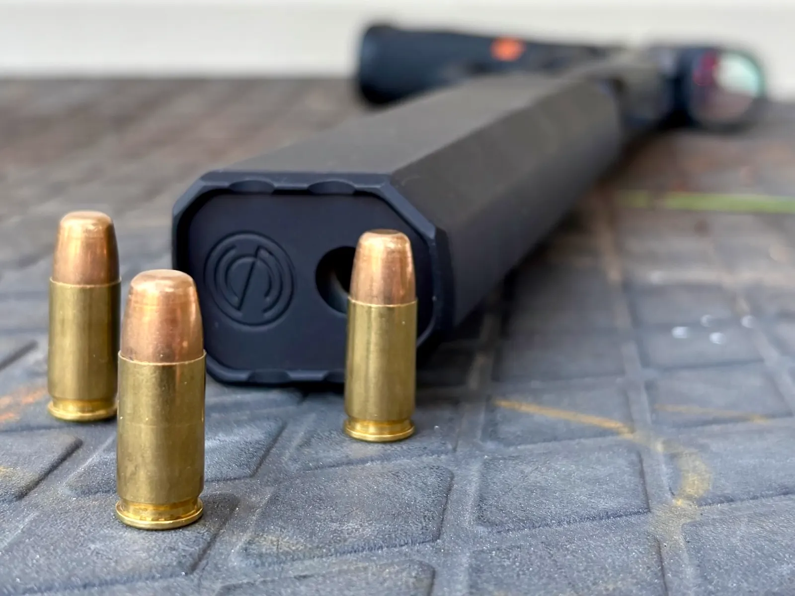 147-grain 9mm rounds standing in front of a SilencerCo Osprey 2.0 suppressor lying flat