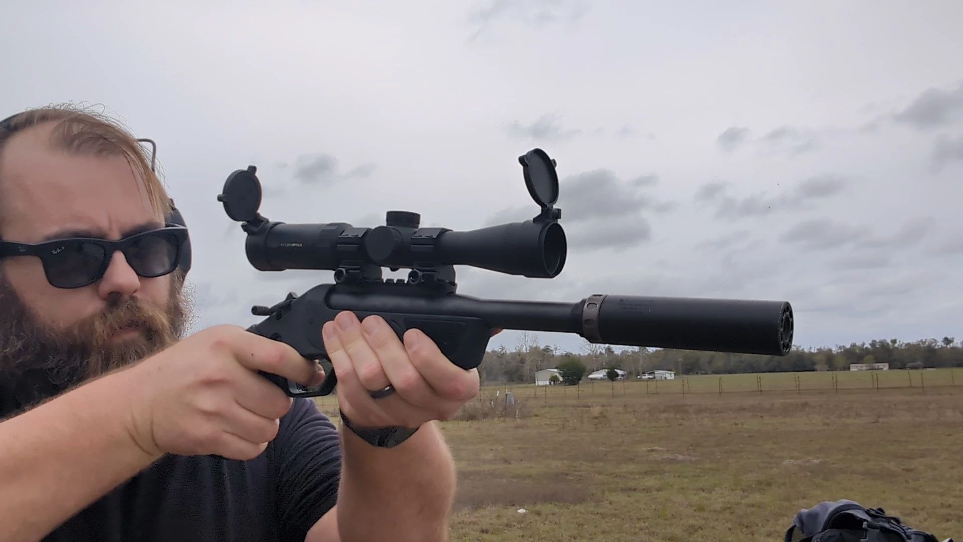 man shooting a suppressed single shot rifle-caliber pistol