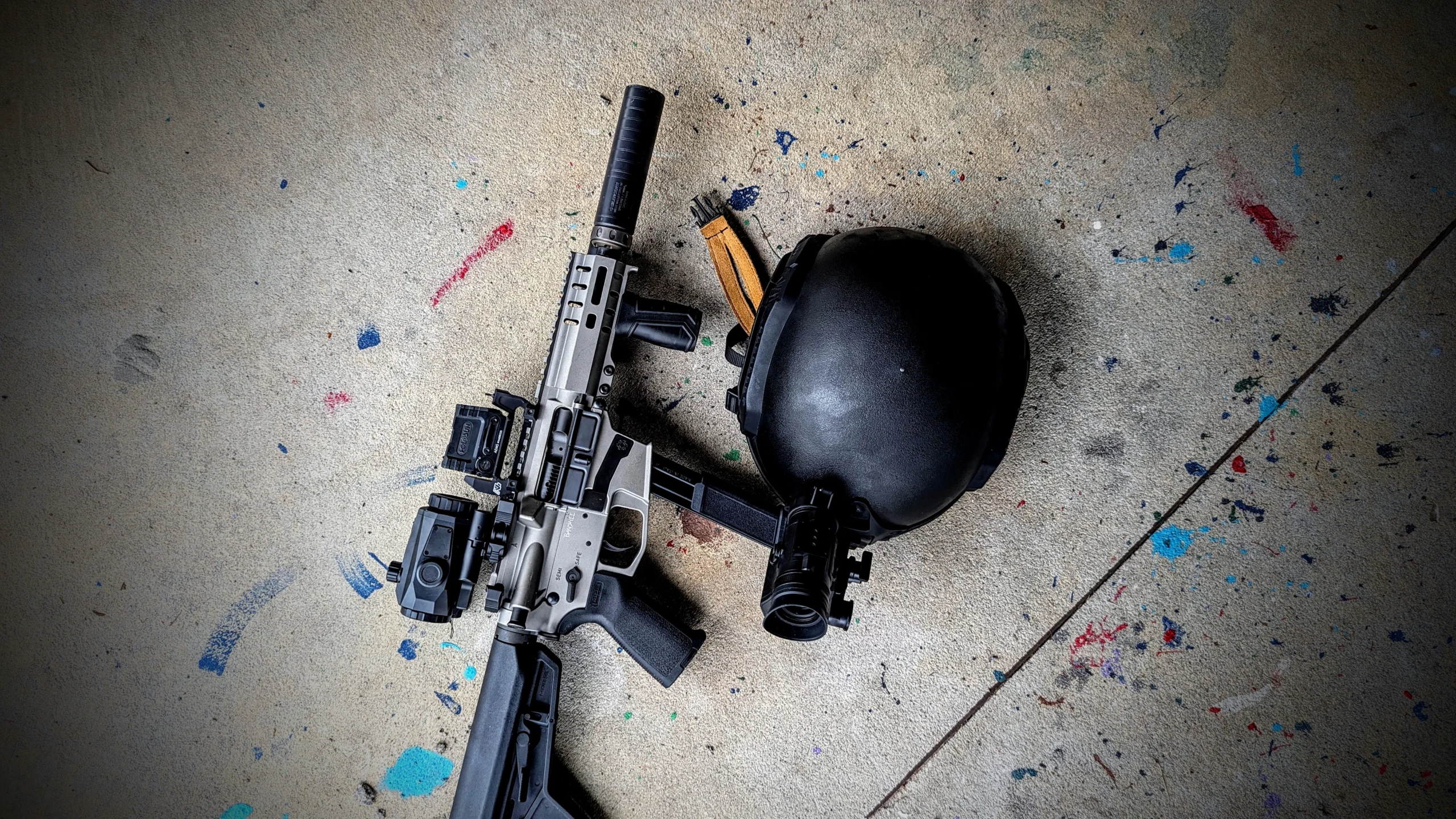 helmet with night vision next to suppressed rifle.