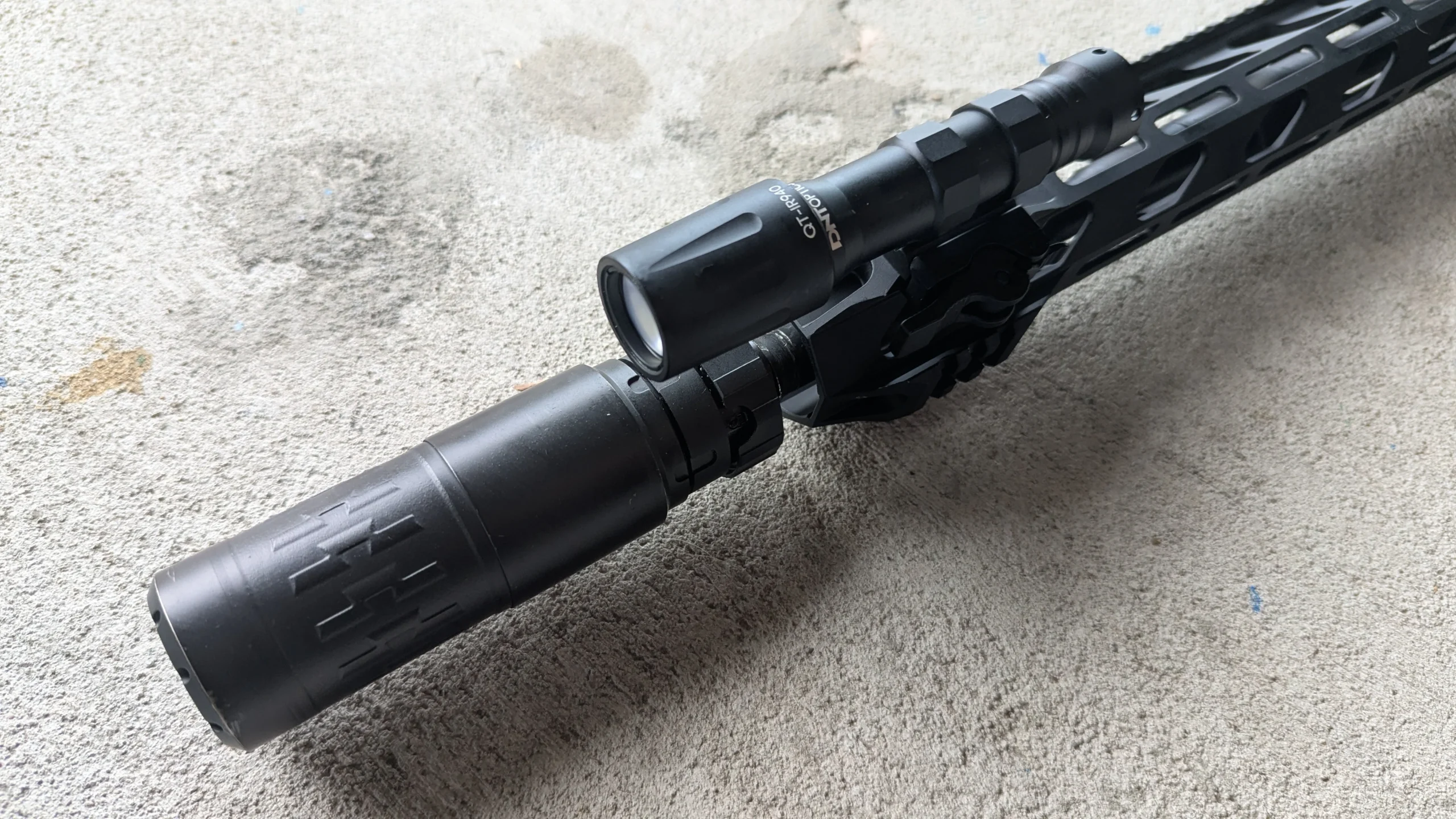 Infrared (IR) laser mounted on rifle barrel behind suppressor