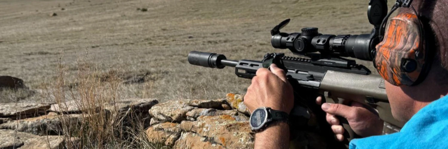 left rear view of man aiming Steyr Aug suppressed with Velos 556K suppressor and mounted with Infitac Thermal scope