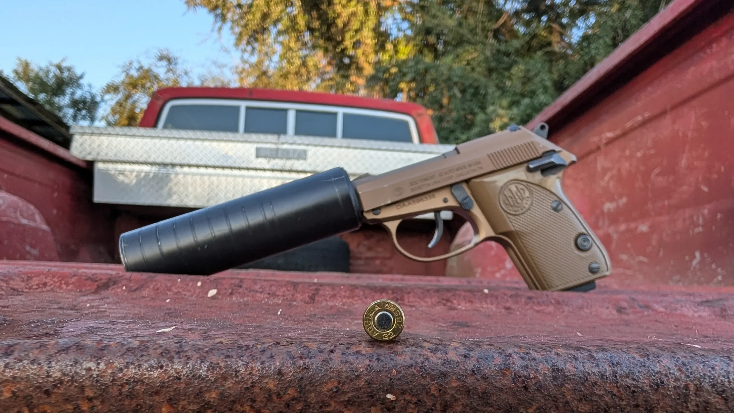 3032 tomcat with silencerco suppressor on a truckbed, with a single round of .32 ACP in the foreground