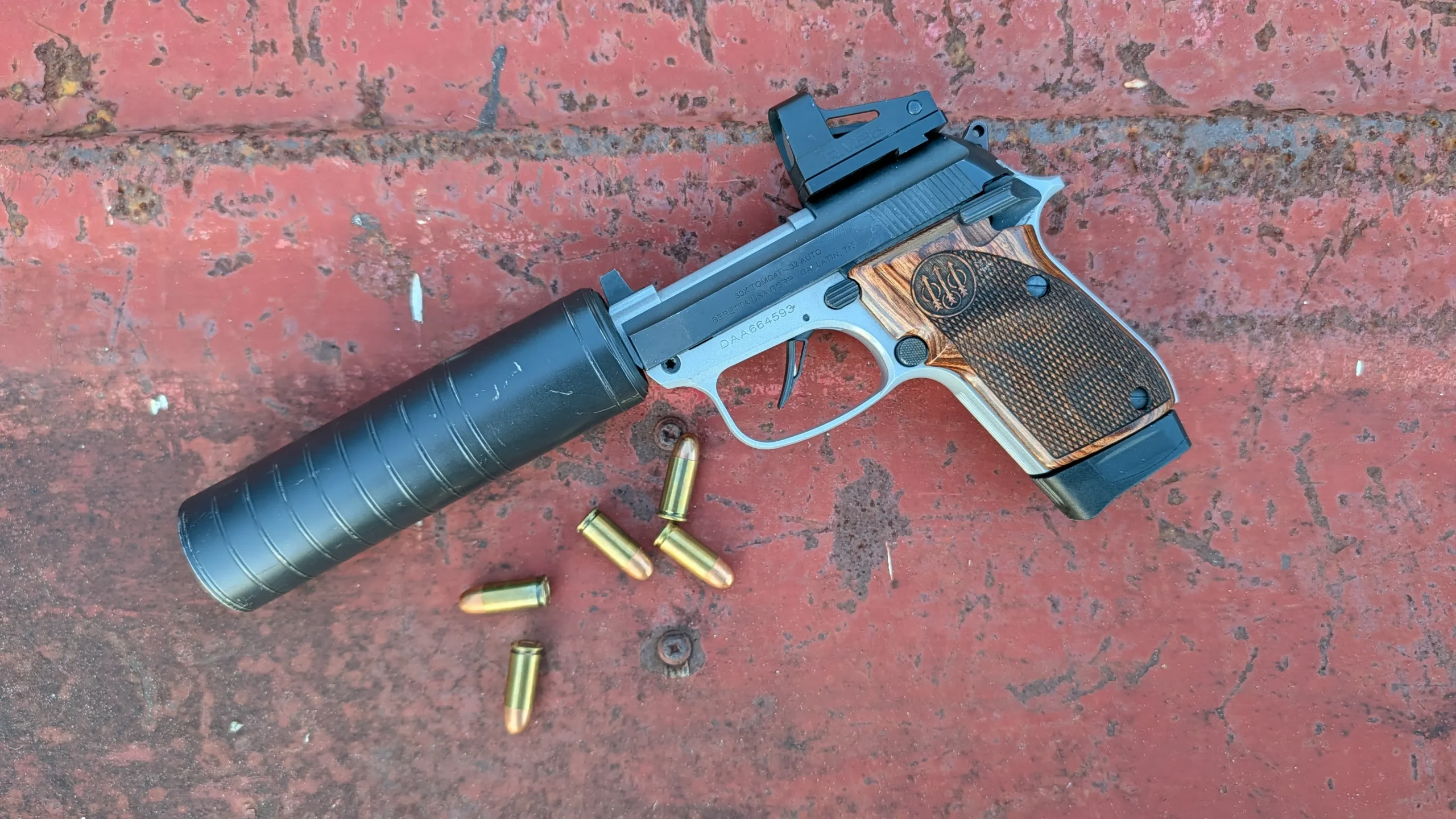 Silencerco Spectre 9 suppressor direct mount attached to Beretta 30x pistol with several .32 ACP rounds near