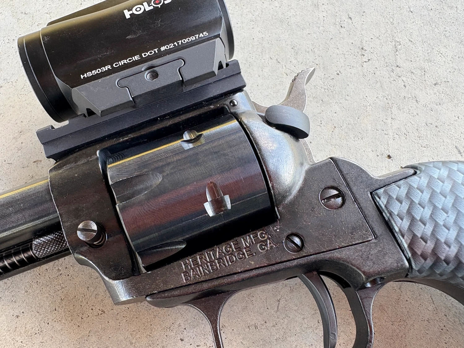 closeup of the finish on the cylinder and frame of a heritage rough rider tactical cowboy revolver, with optic mounted